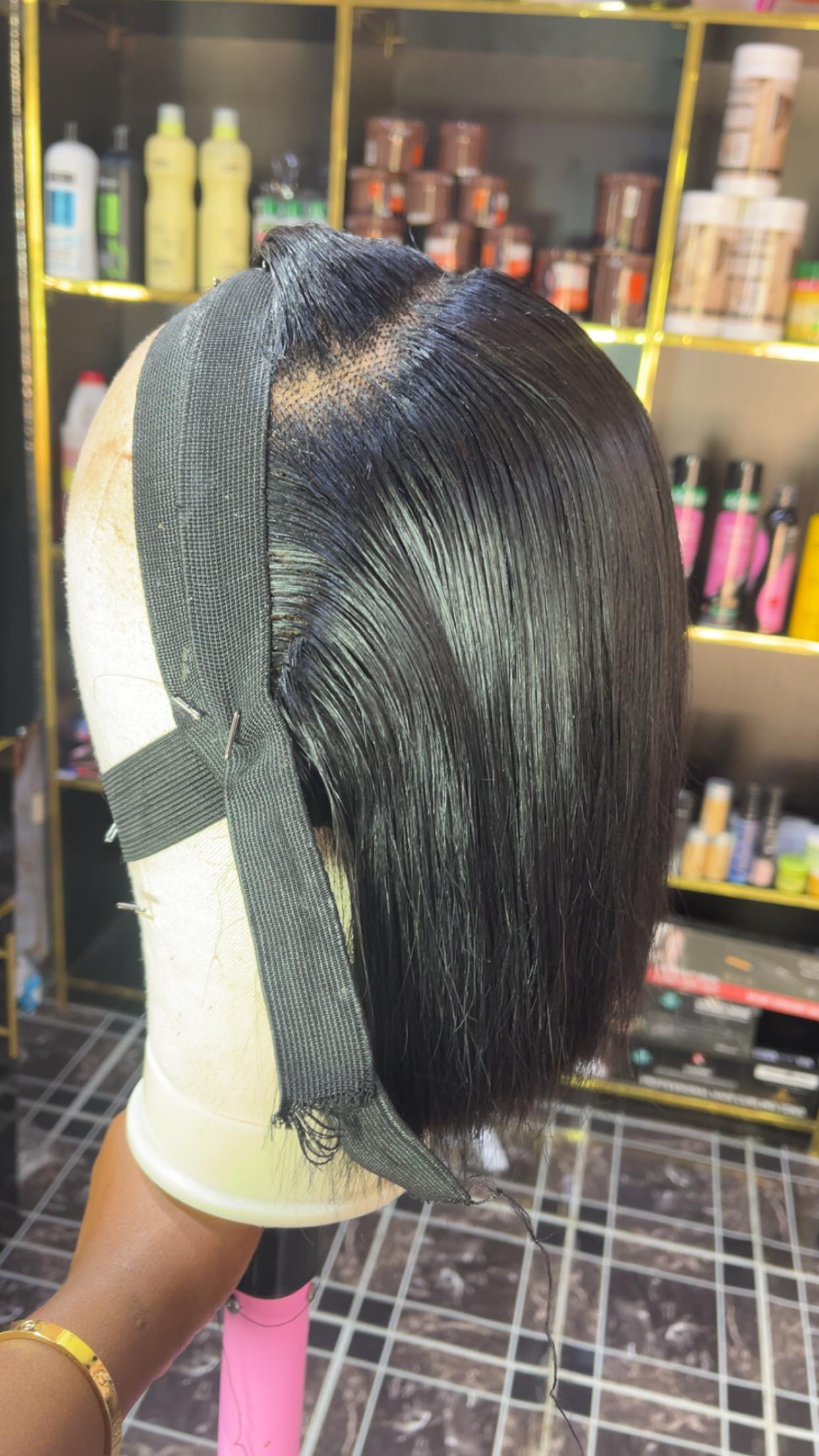 Blunt-cut black bob wig on a styling head, showing the lace and knot work